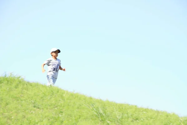 Chico japonés corriendo en la colina (tercer grado en la escuela primaria ) —  Fotos de Stock