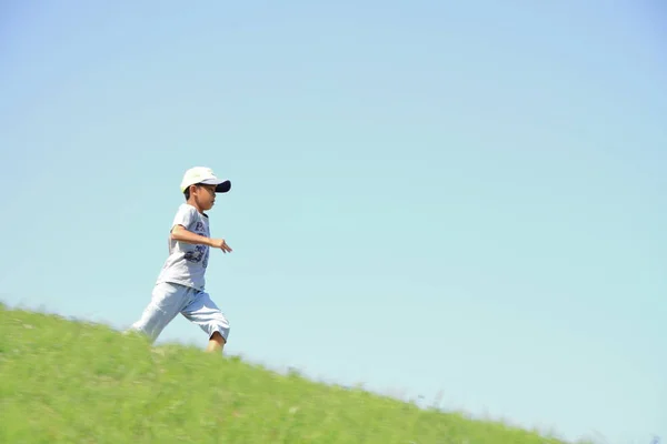 Chico japonés corriendo en la colina (tercer grado en la escuela primaria ) —  Fotos de Stock