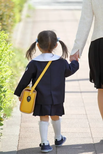(3 歳まで) (後ろ姿の彼女の母の手を握り締めて幼稚園制服を着た日本人の女の子) — ストック写真