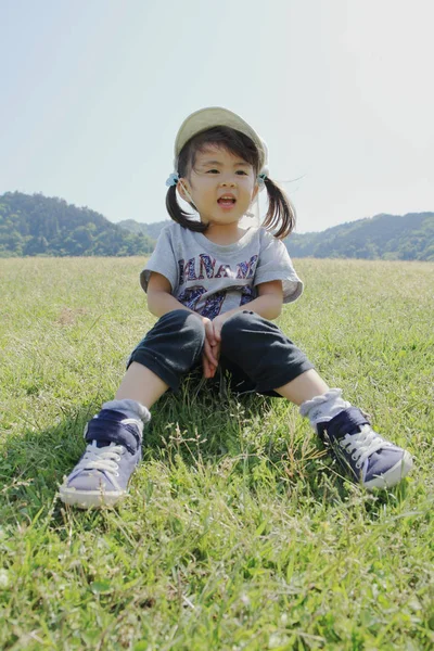 Menina japonesa sentada no gramado (3 anos ) — Fotografia de Stock