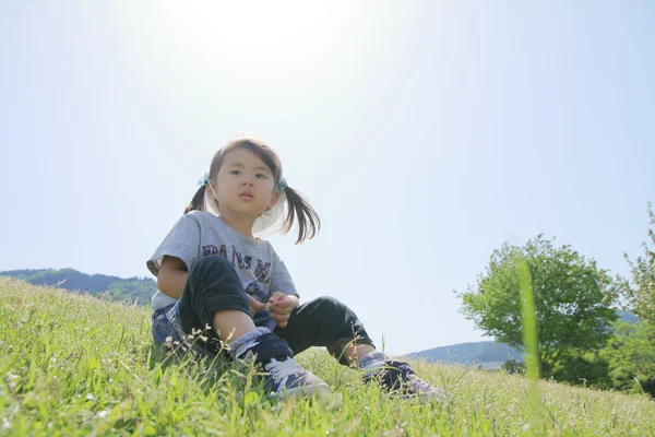 Japanisches Mädchen sitzt auf dem Rasen (3 Jahre alt)) — Stockfoto