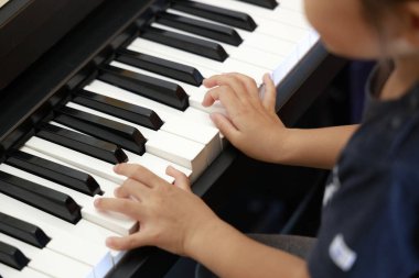 Japanese girl playing a piano (4 years old) clipart