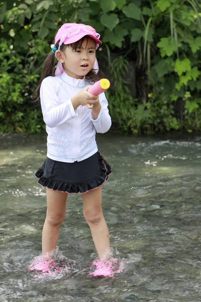 日本女孩在河里玩水枪（4岁）) — 图库照片