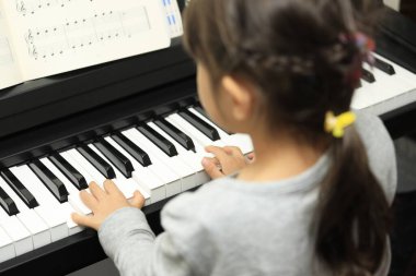 Japanese girl playing a piano (5 years old) clipart