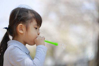 Japon kız mavi gökyüzünün altında baloncukla oynuyor (5 yaşında))