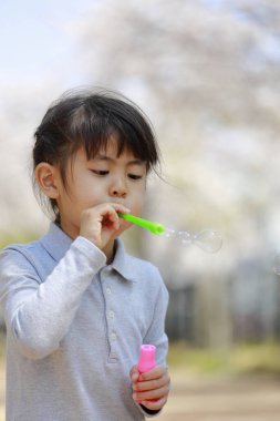 Japon kız mavi gökyüzünün altında baloncukla oynuyor (5 yaşında))