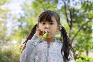 Japon kız yeşil baloncukla oynuyor (5 yaşında))
