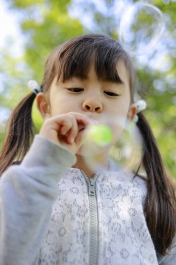 Japon kız yeşil baloncukla oynuyor (5 yaşında))
