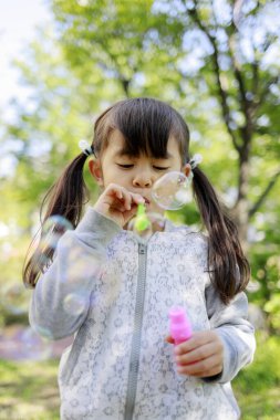 Japon kız yeşil baloncukla oynuyor (5 yaşında))