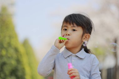 Japon kız mavi gökyüzünün altında baloncukla oynuyor (5 yaşında))