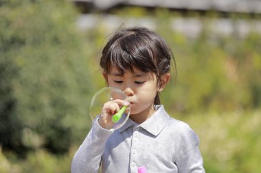Japon kız mavi gökyüzünün altında baloncukla oynuyor (5 yaşında))