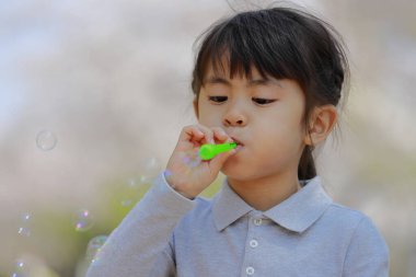 Japon kız mavi gökyüzünün altında baloncukla oynuyor (5 yaşında))