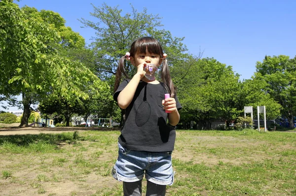 青い空の下で泡と遊ぶ日本人の女の子 — ストック写真