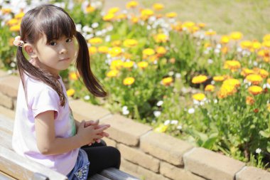 Japon kız çiçek tarhının önünde bankta oturuyor (5 yaşında)