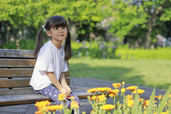 Японская Девушка Сидит Скамейке Перед Клумбой Лет — стоковое фото