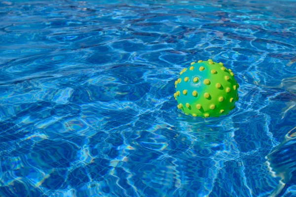 Ball for playing in the pool with spikes swims in a blue pool