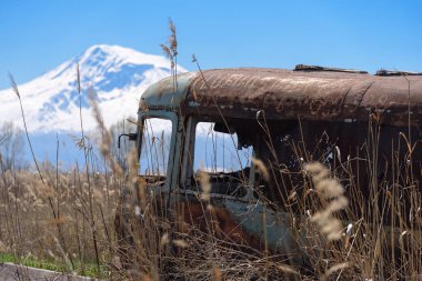 Terk edilmiş ve paslı eski Sovyet Rus otobüs sazlık ve tarım alanları ile Mt. Ararat ortasında arka plan üzerinde