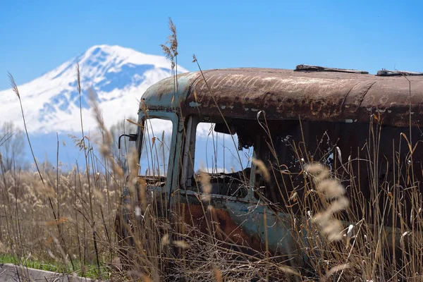 Verlaten en roestige oude Sovjet-Russische bus in het midden van riet en landbouw velden met Mt. Ararat op de achtergrond Stockfoto