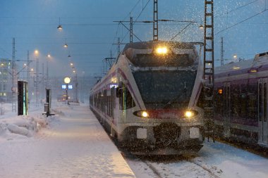 Helsinki, Finlandiya - 6 Şubat 2019: Yerel banliyö treni şafak sökmeden önce yoğun kar fırtınası ile Helsinki merkez tren istasyonuna varıyor.. 