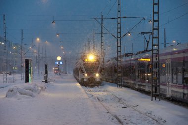 Helsinki, Finlandiya - 6 Şubat 2019: Loş kış sabahının erken saatlerinde yoğun kar fırtınası altında Helsinki merkez tren istasyonuna gelen yerel bir banliyö treni. 