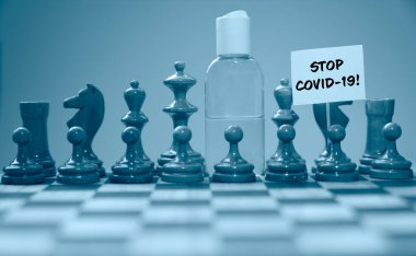 Coronavirus konsepti resim satranç taşları ve satranç tahtasındaki el dezenfektanı covid-19 salgınına karşı küresel mücadeleyi gösteriyor.. 