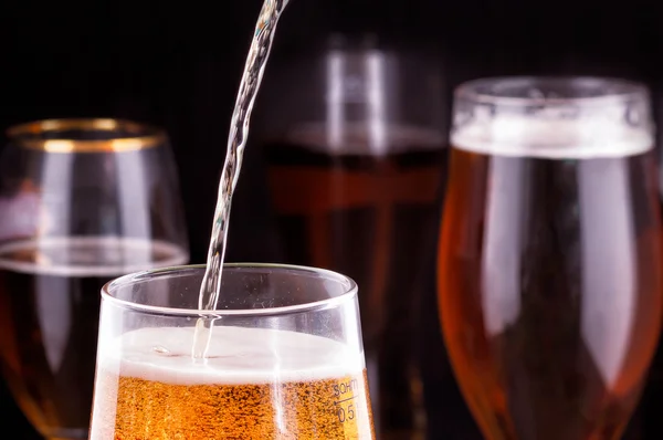 pouring beer into glass on wooden table.