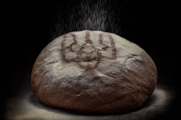 Loaf of wheat bread on rustic background. Urraine emblem — Stock Photo, Image