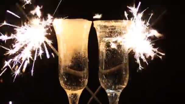 Copas de champán y bengalas sobre fondo brillante con — Vídeo de stock