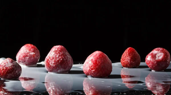 Erdbeere macht Spritzer. isoliert auf schwarzem Hintergrund. Makrofoto einer Erdbeere in Milchspritzern und Tropfen — Stockfoto