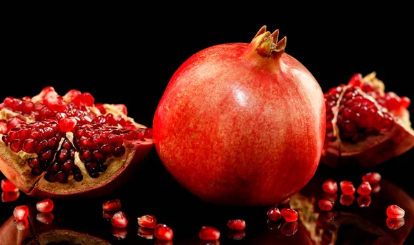 Saftige Granatapfel und seine Hälfte mit Blättern — Stockfoto