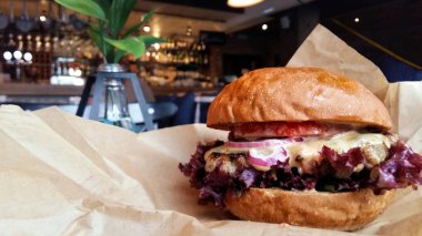Lezzetli taze hamburger ya da çizburger salatası malzemeler ile susam çörek üzerinde kahverengi kağıt pub Bar'da