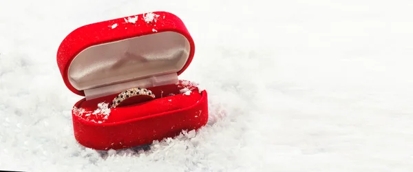 Anelli nuziali in scatola rossa su sfondo bianco neve . — Foto Stock