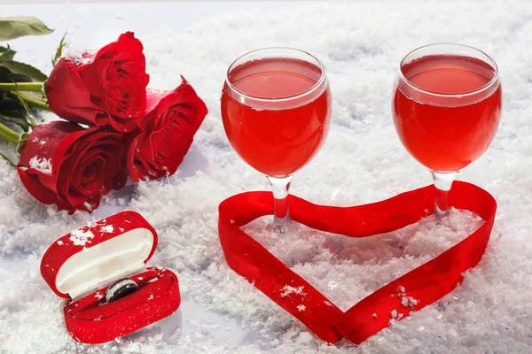 Wedding rings in a box with glases of red wine on white snow background — Stock Photo, Image