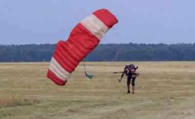 Sutiski, Ukrayna - 24 Haziran 2017: Skydivers iniş sonra bir paraşüt taşır. Skydive Ukrayna olduğunu Sutiski Aerodrome yaklaşık 20 km Vinitsa, Ukrayna'nın güneybatısında bulunan havadalışı Merkezi.