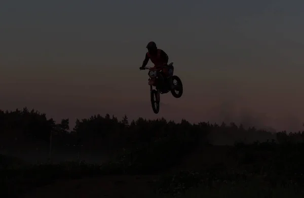 Wazig silhouet van motorcross rijder springen op de berg in de zonsondergang — Stockfoto