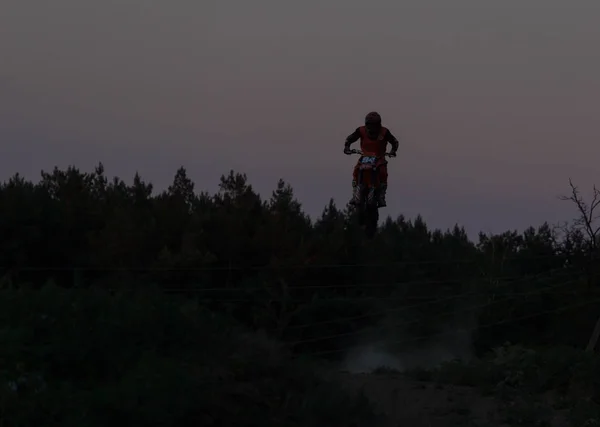 Rozmazané siluety motocross Rider skákání na hoře v západu slunce — Stock fotografie