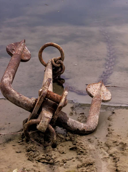 RUSTY ANCHOR WET BEACH SAND AND WHITE SEA-WAVE FOAM — Stock Photo, Image