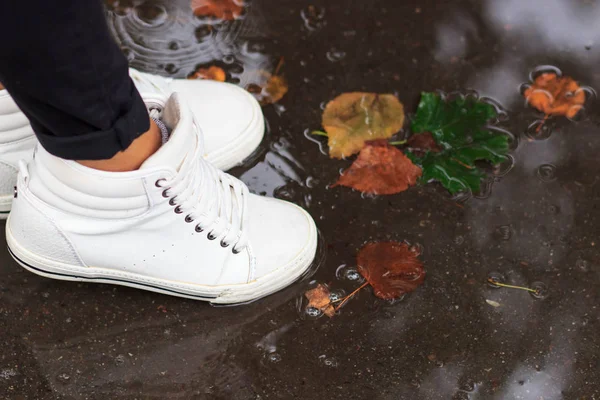 Piernas en zapatos blancos saltando en los charcos de otoño — Foto de Stock