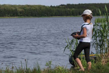 Bir uzaktan kumandalı tekne ile oynayan kız. El yapımı modeli yelkenli Gölü - çocuk tablet ile oynuyor