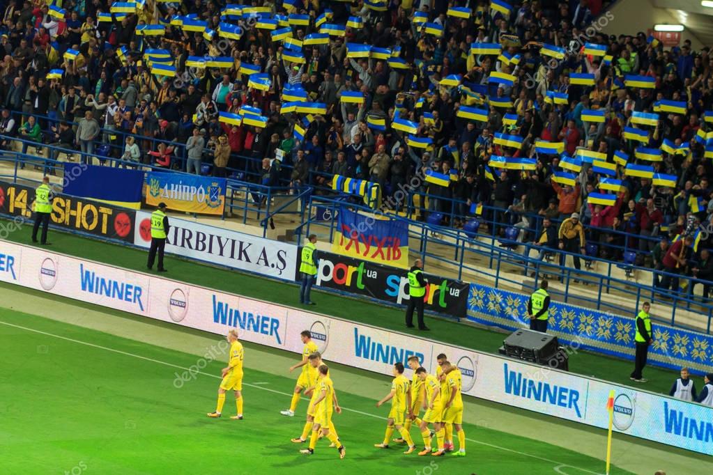 KHARKIV, UKRAINE - SEPTEMBER 2, 2017: Ukrainian fans with huge flag of Ukraine and logo of Football Federation. FIFA World Cup 2018 qualifying match Ukraine - Turkey. Metalist Stadium.