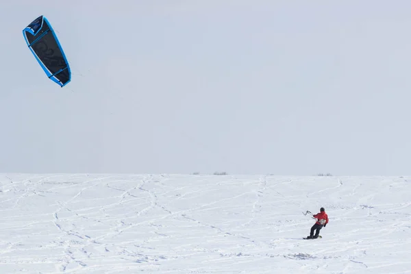 A snowboarder with a kite rides on a frozen lake on free ride. — Stock Photo, Image