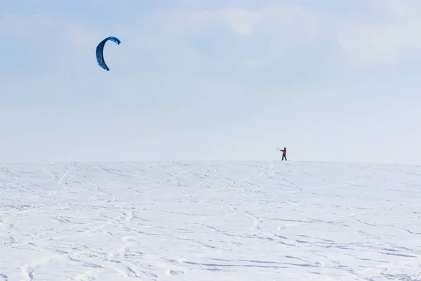 Ένας snowboarder με ένα ΧΑΡΤΑΕΤΟ βόλτες σε μια παγωμένη λίμνη σε ελεύθερη βόλτα. — Φωτογραφία Αρχείου