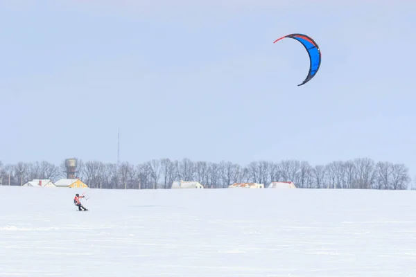 Un snowboarder con una cometa monta en un lago congelado en paseo libre . —  Fotos de Stock