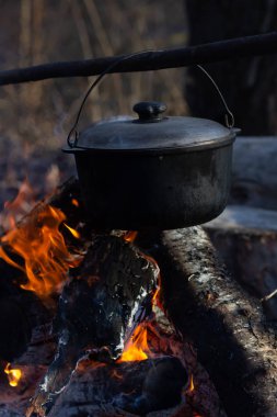 Saha koşullarında yemek pişirmek, piknikte kamp ateşinde demlik pişirmek. Filtrelenmiş resim: çapraz işlenmiş vintage etkisi.