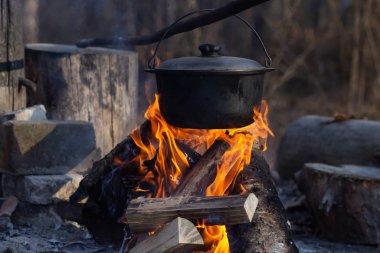 Saha koşullarında yemek pişirmek, piknikte kamp ateşinde demlik pişirmek. Filtrelenmiş resim: çapraz işlenmiş vintage etkisi.