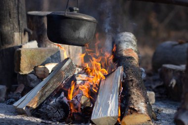 Saha koşullarında yemek pişirmek, piknikte kamp ateşinde demlik pişirmek. Filtrelenmiş resim: çapraz işlenmiş vintage etkisi.