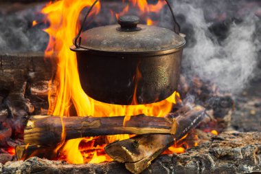 Kamp ateşinde yemek hazırlıyorum. Doldur.