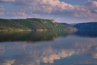 Bulutlu bir günde göl boyunca yürürken, bulutlar suya yansıyor, bir ayna gibi. Doğa