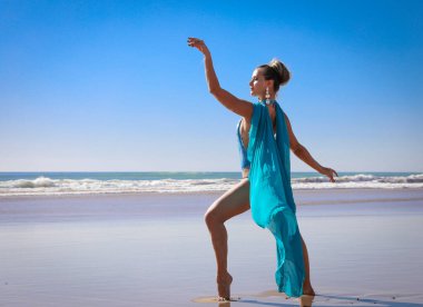 Okyanusta şifon pelerinli mavi mayolu güzel bir genç kız..