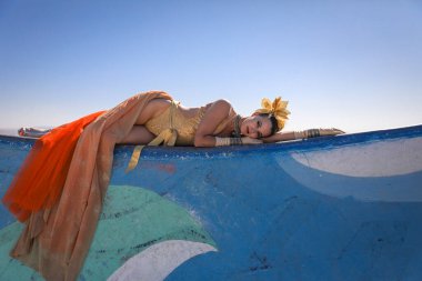 Seksi turuncu takım elbiseli güzel bir genç kız yaz günü dışarıda poz verir..